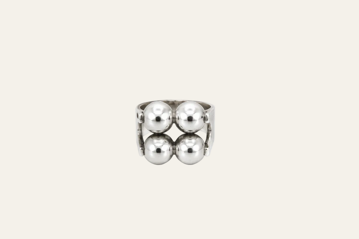 A silver-toned metal ring featuring four large, polished spherical beads arranged in a symmetrical double-row design on a plain white background.